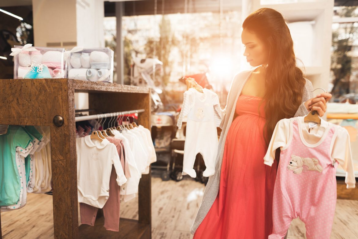 A pregnant woman shopping for baby clothes during her second trimester