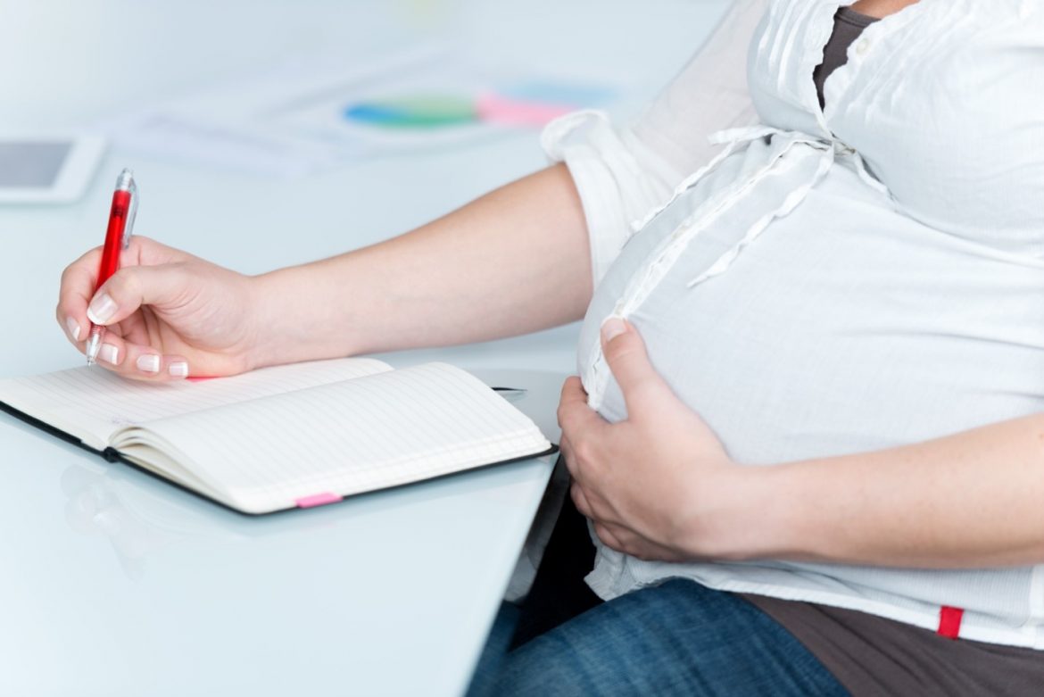 a pregnant woman writing in a journal