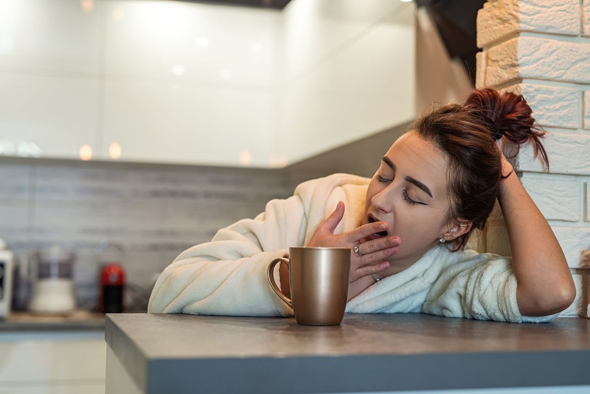 positive signs after embryo transfer - a woman leaning on a counter yawning